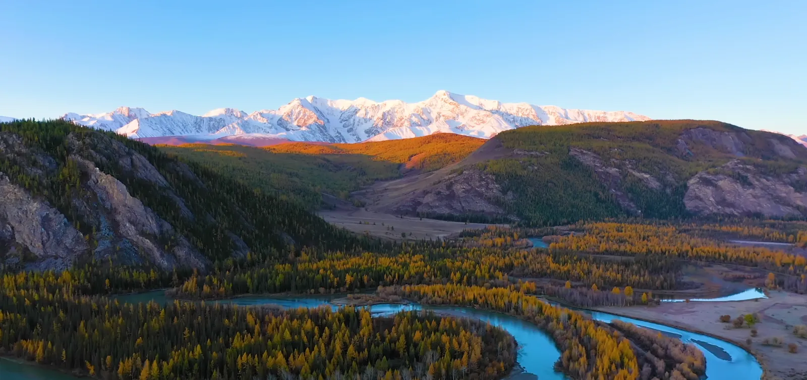 Aerial view of an autumn river valley winding through mountains